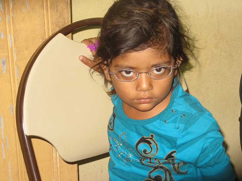 Young girl sitting in chair with new eyeglasses on