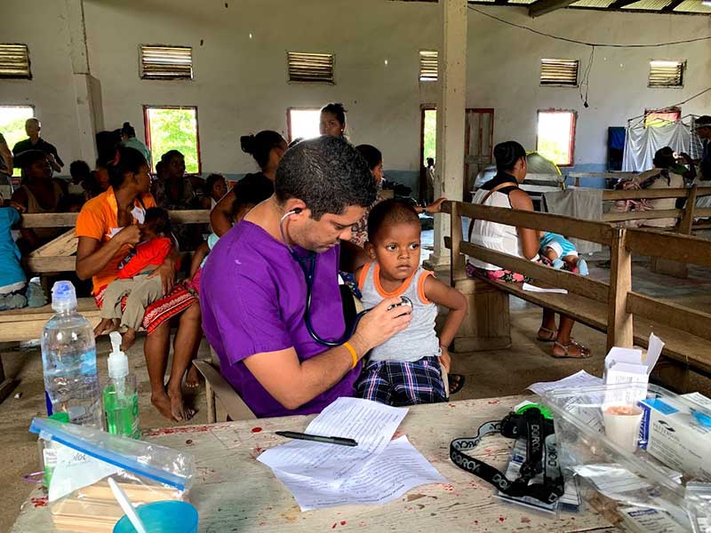child receiving a medical exam - doc in purple scrub