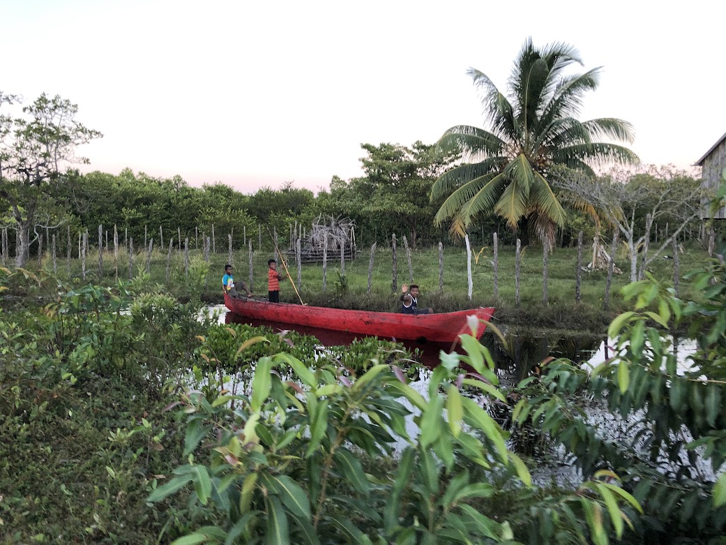 children rowing a red canoe through a canal